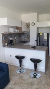 a kitchen with two bar stools in front of a counter at Excelente apartamento Santa Marta Colombia in Santa Marta