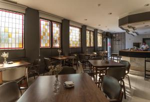 un restaurante con mesas y sillas de madera y ventanas en Hotel Don Carmelo, en Ávila