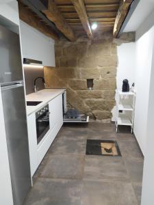 cocina con electrodomésticos blancos y pared de piedra en Ca la Francisqueta, La Tina i el Deso Apartament Solsona en Solsona