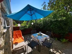 een tafel en stoelen met een blauwe parasol bij Apartments Relax Punat in Punat