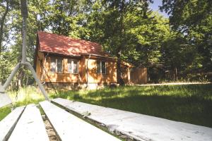 an old house in the grass next to a wooden bridge at Rozetta Vendégház in Kismaros