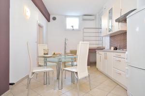 a kitchen with a table and white chairs at Apartments Nautilus in Pula
