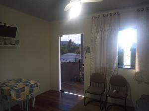 a living room with a table and chairs and a window at Nosso Pedacinho in Abraão