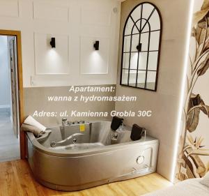 a bath tub in a room with a mirror at Jacuzzi Apartamenty Gdańsk - RELAX Apartments in Gdańsk