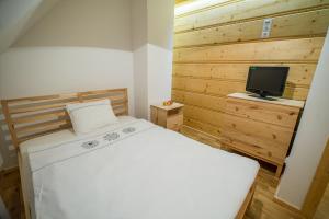 Schlafzimmer mit einem weißen Bett und einem TV in der Unterkunft Chata Smagula in Korbielów