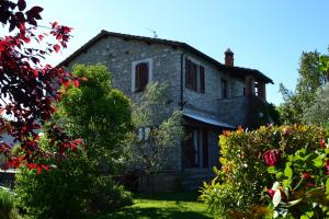 an old stone house with flowers in the yard at Le Macchie in Baschi