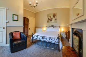 a bedroom with a bed and a chair and a fireplace at Pannett House Guesthouse in Whitby