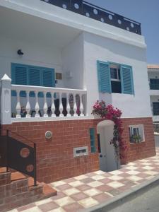 ein weißes Haus mit blauen Fenstern und Ziegelwand in der Unterkunft Apartamento Trini in La Jaca