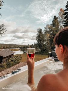 a woman sitting in a bath tub holding a glass of wine at Ollero Eco Lodge (including a glass igloo) in Rovaniemi +50 photos