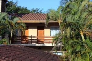 a house with palm trees in front of it at Pousada do Pinheiro in Camburi