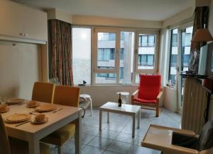 a living room with a table and chairs and a window at Le 7ème Ciel Westende in Middelkerke