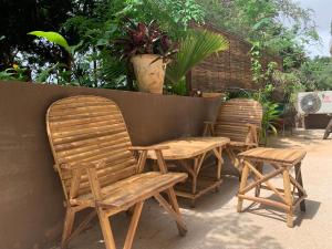 duas cadeiras de madeira e uma mesa ao lado de uma parede em Appartement cosy, calme et très bien placé à ouakam Dakar em Dakar
