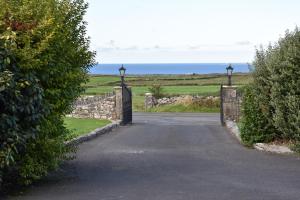 a gate to a road with the ocean in the background at Aran View Holiday Homes Doolin - The Courtyard House - Sleeps 9 in Knockfin Cross Roads