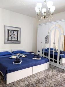 1 Schlafzimmer mit 2 Betten mit blauer Bettwäsche und einem Kronleuchter in der Unterkunft Silia's Maisonette in Marsaskala