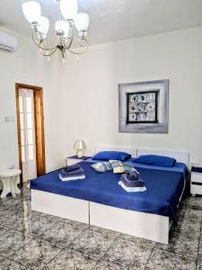 a bedroom with a bed with blue sheets and a chandelier at Silia's Maisonette in Marsaskala