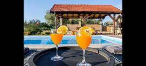 two glasses of orange juice on a table near a swimming pool at Olive Tree House with Jacuzzi, WiFi and 40m2 pool in Širitovci
