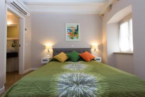 - une chambre avec un lit vert et des oreillers colorés dans l'établissement Villa Flores Room, à Dubrovnik