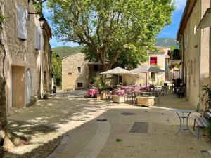 an alley with tables and umbrellas in a village at Maison & Jardin Coeur Luberon classé 4 étoiles in Peypin-dʼAigues