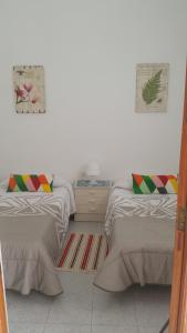 a bedroom with two beds and a white wall at Casa el Hoyo in Hermigua