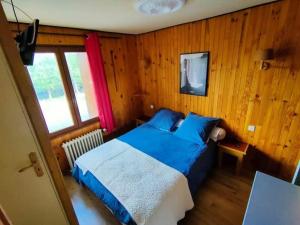 a bedroom with a blue bed and a window at Chalet du Mont Lozère in Cubières