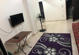 een woonkamer met een tv en een tafel en een tapijt bij AC, Wi-Fi Shahrazad Beach Apartment-2 in Alexandrië