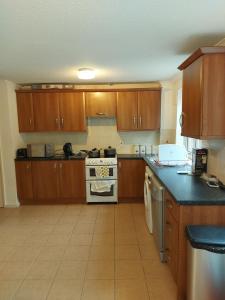 a kitchen with wooden cabinets and a stove top oven at Spacious and Serene Stay near Milton Keynes centre in Willen