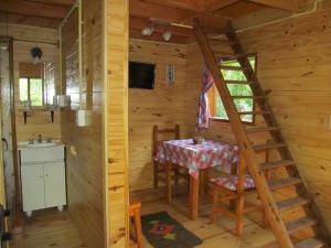 una habitación con una mesa y una escalera en una cabaña de madera en Hospedaje Las Gardenias en Lago Puelo