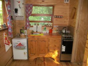 a kitchen with a sink and a stove and a refrigerator at Hospedaje Las Gardenias in Lago Puelo +17 photos