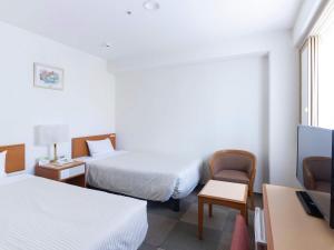 a hotel room with two beds and a flat screen tv at Hotel Wing Port Nagasaki in Nagasaki +24 photos