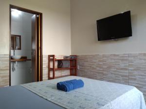 a bedroom with a bed with a flat screen tv on the wall at Pousada Marimbá in Trindade