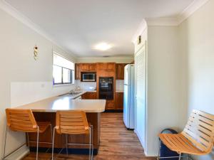 a kitchen with a table and chairs and a refrigerator at Noraville Summer House in Norah Head