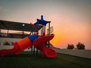 a playground with a slide in the grass with the sunset at Desert Dune Farmhouse - By Seven Elements in Ras al Khaimah