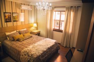 a bedroom with a bed with a chandelier and a window at Apto Panorâmico 3 quadras da Rua Coberta in Gramado