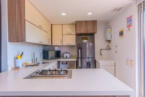 a kitchen with white counter tops and wooden cabinets at Beautiful Apartment UltraFast Internet /El Poblado in Medellín