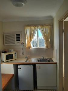 a kitchen with a stove top oven and a microwave at Country Rose Motel Warwick in Warwick