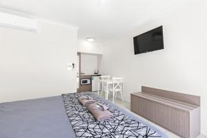 a living room with a flat screen tv on a wall at Surf Beach Motel Coffs in Coffs Harbour