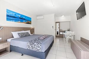 a bedroom with a bed and a kitchen with a table at Surf Beach Motel Coffs in Coffs Harbour