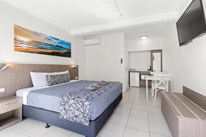 a bedroom with a bed and a kitchen with a table at Surf Beach Motel Coffs in Coffs Harbour