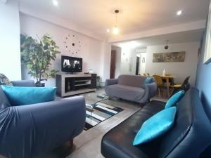 Cusco Cozy Apartment في كوسكو: غرفة معيشة مع أرائك زرقاء وتلفزيون