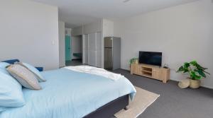 a bedroom with a bed and a flat screen tv at Studio Apartment, Centre Of Airlie With Sea Views in Airlie Beach