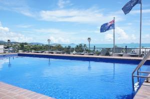 a large swimming pool with two flags on a building at Studio Apartment, Centre Of Airlie With Sea Views in Airlie Beach