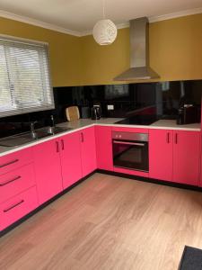 a kitchen with pink cabinets and a sink at Bruny Ocean Cottage in Alonnah +13 photos