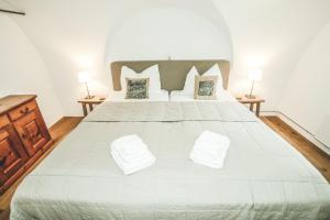 1 dormitorio con 1 cama grande con sábanas y almohadas blancas en Il Maschun im historischen Engadinerhaus, en Scuol