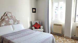 1 dormitorio con 1 cama y 1 silla con almohada roja en Hostal Martes Cáceres Plaza Mayor - Tercer piso SIN ascensor, en Cáceres