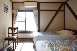 1 dormitorio con 2 camas y ventana en Sakura Guest House, en Takayama