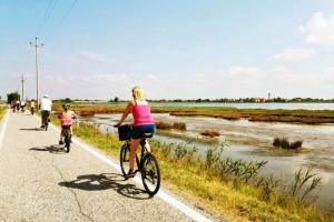a woman and a child riding bikes down a road at Casa EUROPA in Cavallino-Treporti