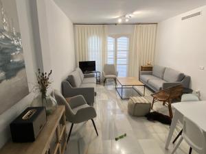 een woonkamer met banken en stoelen en een televisie bij Apartamento en Urbanización Mezquida Javea recién reformado in Jávea