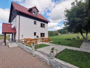 a white building with a red roof and benches at Plitvice Antico in Gornji Babin Potok