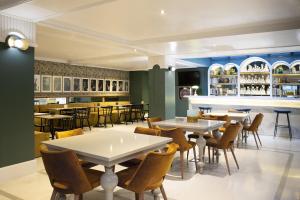 a restaurant with tables and chairs and a bar at Petit Palace Puerta de Triana in Seville