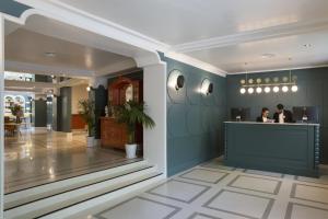 a lobby of a restaurant with two people at a counter at Petit Palace Puerta de Triana in Seville